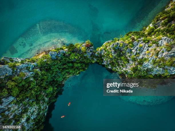 drone view on rocks and canoes floating on turquoise water in the halong bay, vietnam - vietnam landscapes stock pictures, royalty-free photos & images