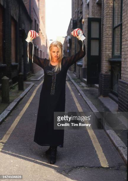 Canadian actress Pamela Anderson wearing boxing gloves with a stars and stripes design, London, circa 1996.