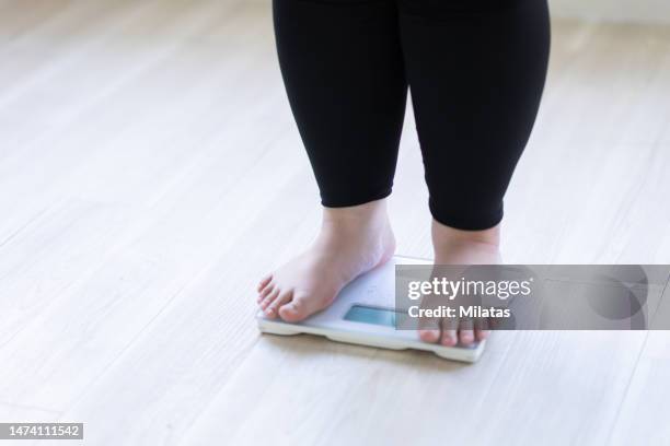 a woman's feet on a weight scale - obesity imagens e fotografias de stock