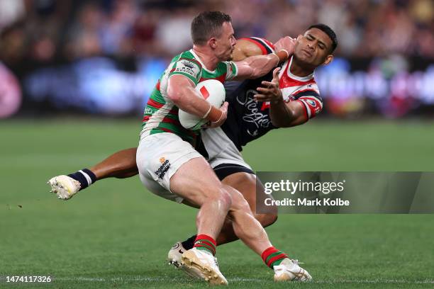 Damien Cook of the Rabbitohs fends off Daniel Tupou of the Roosters is tackled during the round three NRL match between Sydney Roosters and South...