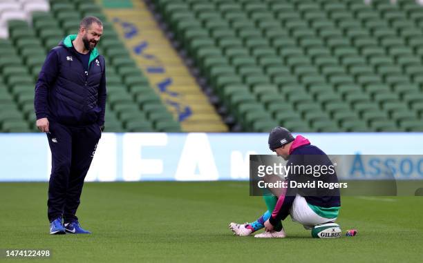 Johnny Sexton the Ireland captain ties his boots as head coach Andy Farrell looks on during the Ireland captain's run at the Aviva Stadium on March...