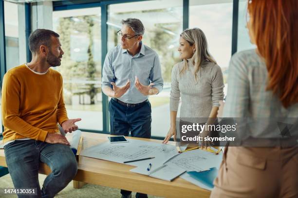 building contractors talking while working on plans in the office. - real estate developer stock pictures, royalty-free photos & images