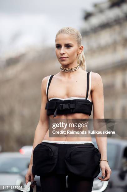 Caroline Caro Daur wears black cropped top, mini skirt with bags, tights, ankle boots, white bag outside the Miu Miu show during Paris Fashion Week...