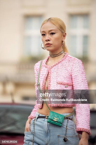 Niki Wu Jie wears pink cropped jacket, denim jeans with belts, white pointed heels, green micro bag, metallic bag, necklace, earrings outside the...