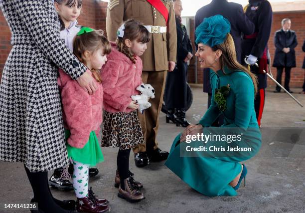 Catherine, Princess of Wales presents a traditional sprig of shamrock to an Officers children during the St. Patrick's Day Parade at Mons Barracks on...