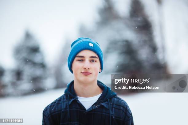 teenage boy outdoors enjoying snowfall - knit hat stockfoto's en -beelden