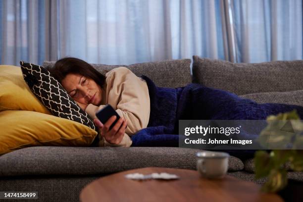 woman on sofa using cell phone - verlaten stockfoto's en -beelden