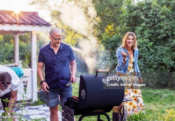 people having barbecue in garden - bbq smoker stock pictures, royalty-free photos & images