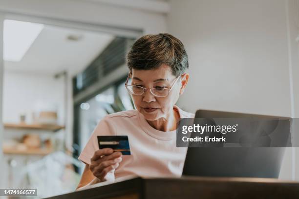 senior adult woman trying to using her credit card with online shopping. - inexpensive stockfoto's en -beelden