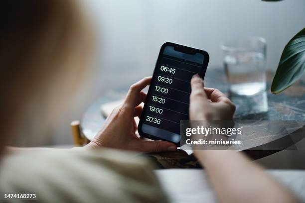 close up of woman hands snoozing alarm on a mobile phone screen in the morning - alarm stockfoto's en -beelden