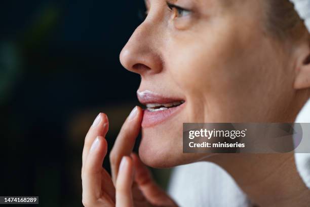 close up photo of a smiling woman applying moisturising chapstick on lips in the morning - lip balm stock pictures, royalty-free photos & images