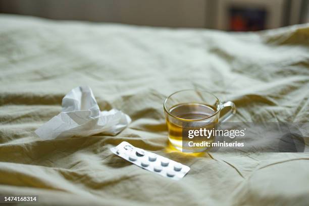 cup of tea, paper tissue and pills on the bed at home - handkerchief stock pictures, royalty-free photos & images