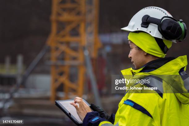 female engineer using digital tablet at building site - oorbeschermer stockfoto's en -beelden