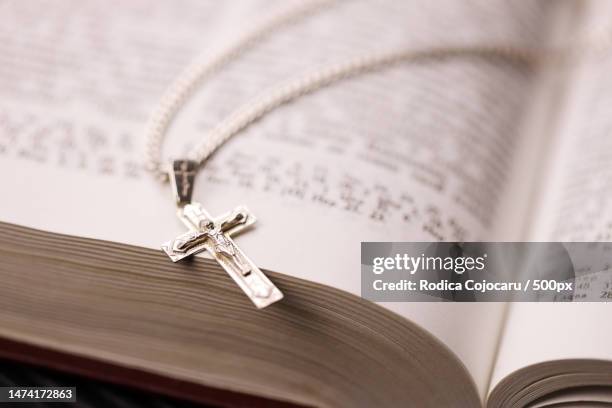 silver necklace with crucifix cross on christian holy bible book on black wooden table asking bless,romania - rosary beads stock pictures, royalty-free photos & images