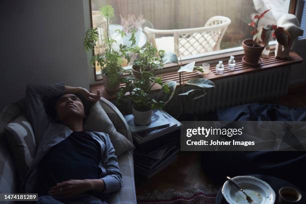 sad man facing depression lying in bed - hypochondria - fotografias e filmes do acervo