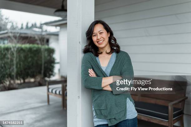woman on front patio of modern farmhouse style home - mature women portrait asian stock pictures, royalty-free photos & images