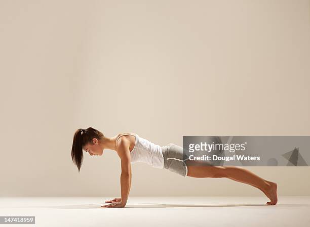 woman doing press up on white set. - opdrukken stockfoto's en -beelden