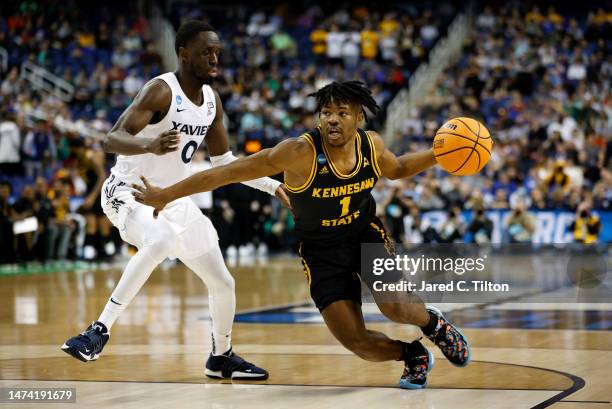 Terrell Burden of the Kennesaw State Owls dribbles the ball against Souley Boum of the Xavier Musketeers during the first half in the first round of...