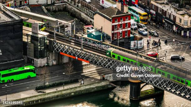 vue aérienne du train vert dart à dublin irlande, vue aérienne du train / tram traversant le pont,vue aérienne du train dans le centre-ville, train sur le pont de la rivière dans le centre-ville,train sur le dublin butt bridge,transports publics dans - dublin dart photos et images de collection