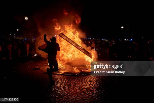 Protester throws a fence onto a burning barricade at Place de la Concorde as demonstrations continue for a second straight night against the French...