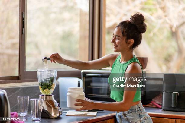 giovane donna ispanica che taglia gli ingredienti per frullato sano in cucina - collagene foto e immagini stock