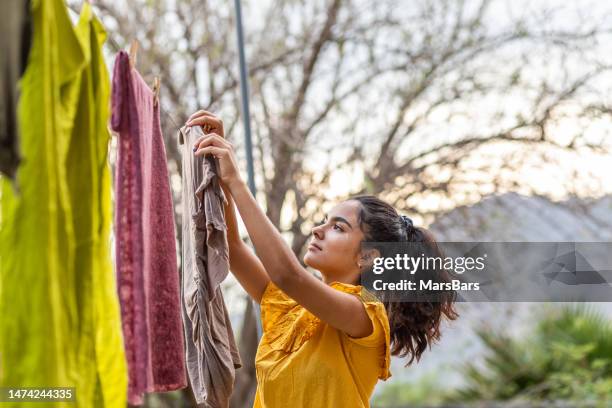 junge frau hängt wäsche zum trocknen an die wäscheleine: nachhaltigkeitskonzept - trocknen stock-fotos und bilder