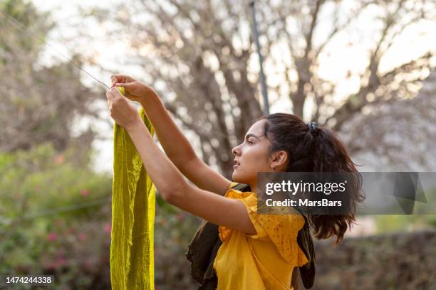 young woman hanging clothes to dry in clothesline: sustainability concept - hair back stock pictures, royalty-free photos & images