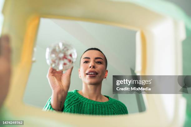 une jeune femme heureuse collecte du plastique pour le recyclage - jetée photos et images de collection