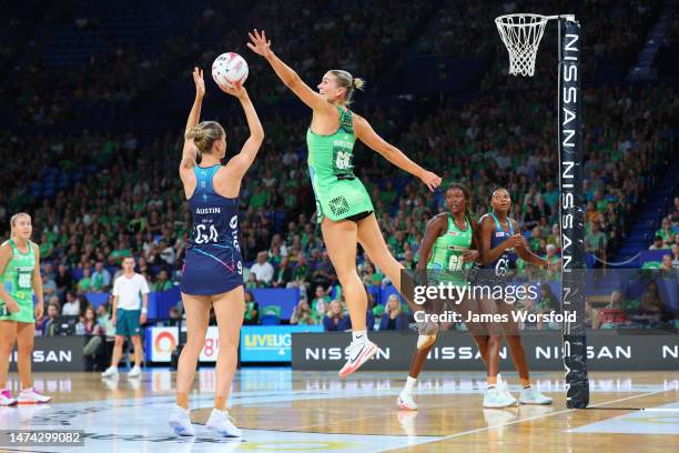 Courtney Bruce of the fever leaps up to attempt to block the shot from Kiera Austin of the vixens during the round one Super Netball match between...