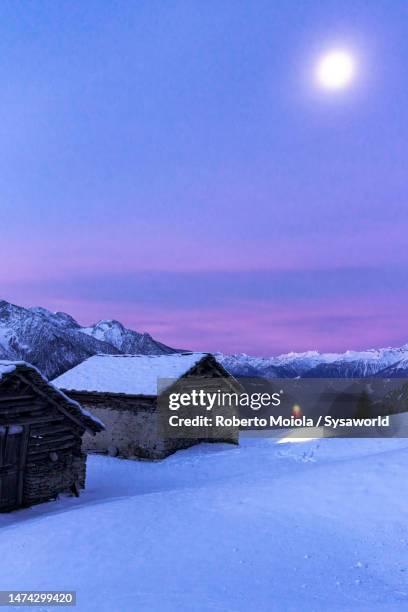 hiker with snowshoes admiring the snowy huts - schneeschuhwandern stock-fotos und bilder