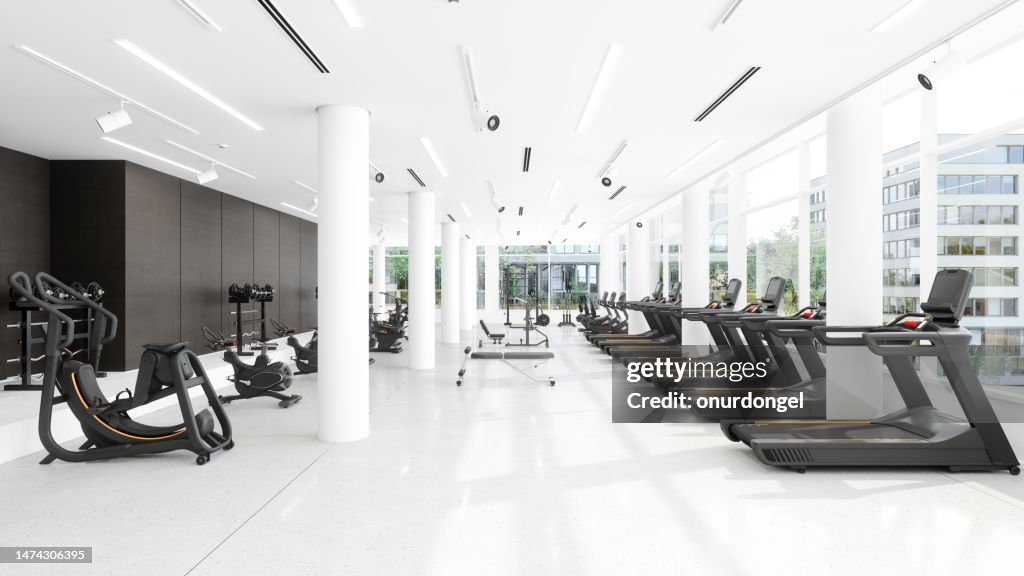 Modernes Fitnessstudio mit Laufbändern, Heimtrainern, Sportgeräten und Blick auf die Stadt durch das Fenster