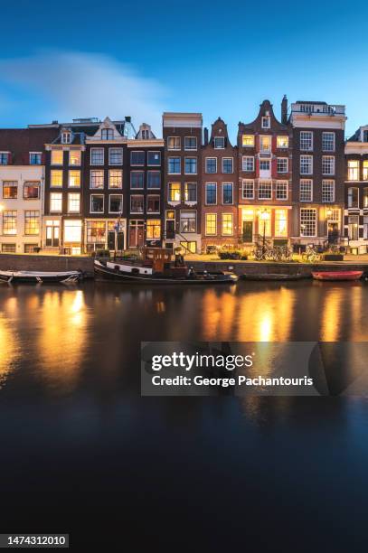 canal houses and boats in amsterdam, holland at dusk - amsterdam sunrise stockfoto's en -beelden