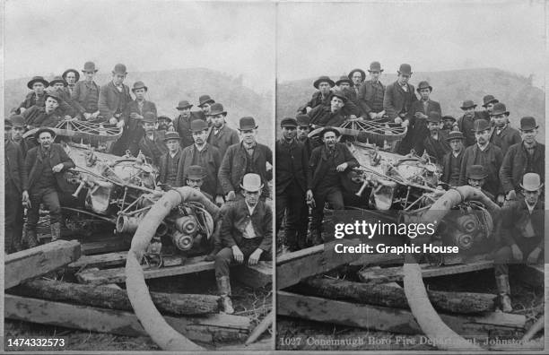 Stereoscopic image showing members of the Conemaugh Boro Fire Department posing around an overturned fire engine, following the Johnstown Flood,...