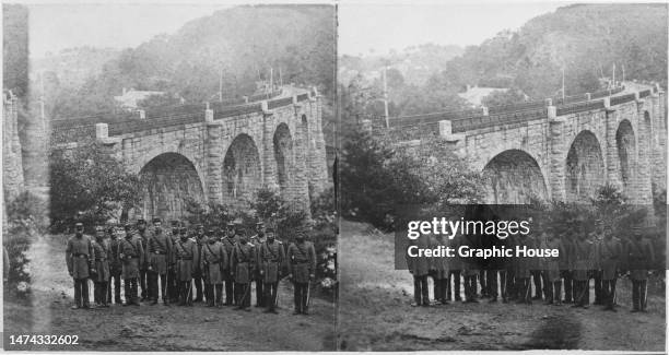 Stereoscopic image showing Confederate Army soldiers posing with an arch bridge in the background, United States, circa 1863.