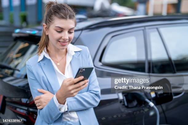 young woman charging her electric car - 蓄電池 ストックフォトと画像