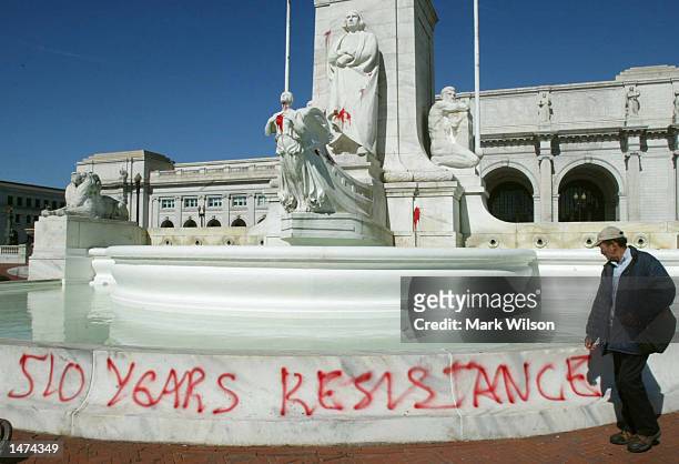 Man walks past a statue of Christopher Columbus that was vandalized with red paint at Union Station October 14, 2002 in Washington, D.C. The fountain...