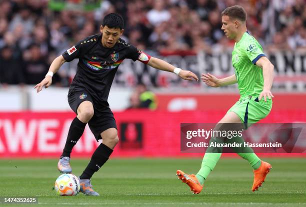 Wataru Endo of VfB Stuttgart controls the ball whilst under pressure from Yannick Gerhardt of VfL Wolfsburg during the Bundesliga match between VfB...