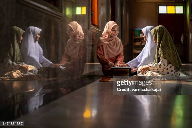 beautiful muslim girl in hijab teaching kids to read quran in mosque - beautiful arabian girls stock pictures, royalty-free photos & images
