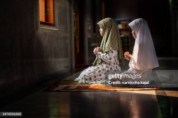 muslim girl in hijab sitting in the mosque praying - roman god stockfoto's en -beelden