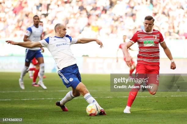 Henning Matriciani of FC Schalke 04 intercepts to deny Ermedin Demirovic of FC Augsburg during the Bundesliga match between FC Augsburg and FC...