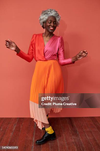 senior woman dancing in red dress - afro caribbean portrait stock pictures, royalty-free photos & images