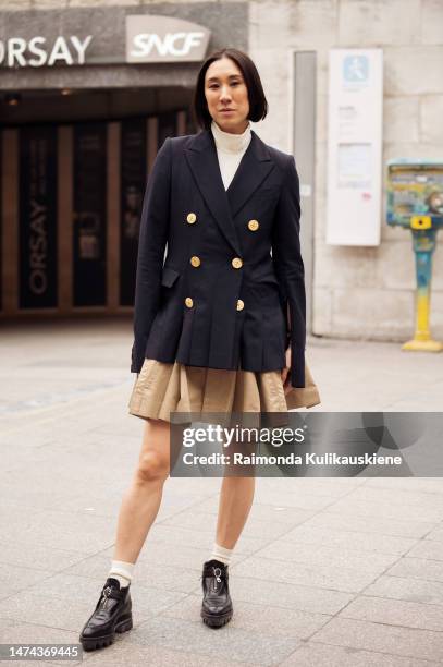 Eva Chen wears double breasted navy blazer, beige pleated skirt, socks, black shoes outside the Louis Vuitton show during Paris Fashion Week -...