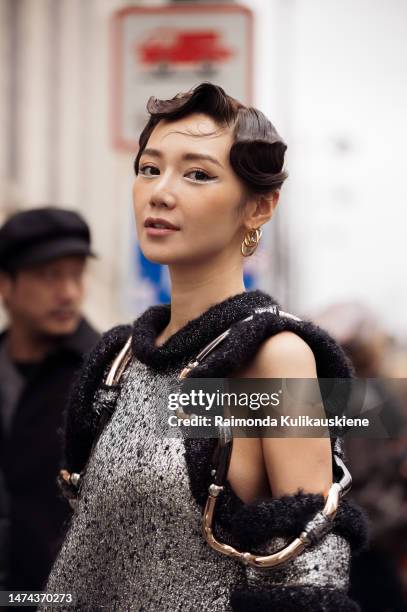 Guest is seen wearing gold Louis Vuitton earrings, a silver and black wool with wavy large borders and cut-out shoulders Louis Vuitton dress, a grey...