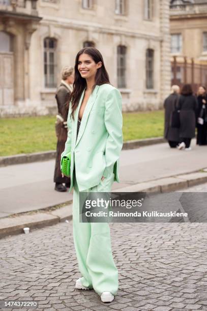 Sara Sampaio wears a pale green oversized blazer jacket, matching pale green wide legs pants, a neon green shiny leather handbag outside the Stella...