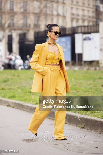 Anna Rosa Vitiello wears yellow blazer, pants, laced top, black bag, gold big chain necklace, golden shell earrings, and black sunglasses outside the...