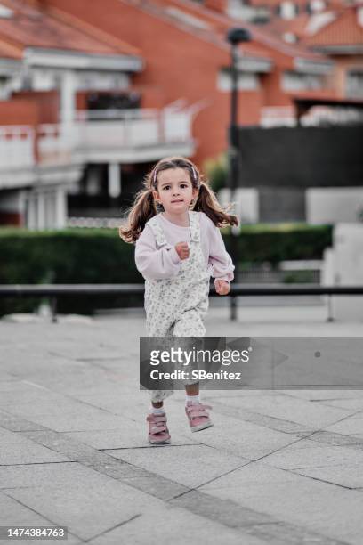 5 year old girl running down a street in the city - ir em frente imagens e fotografias de stock
