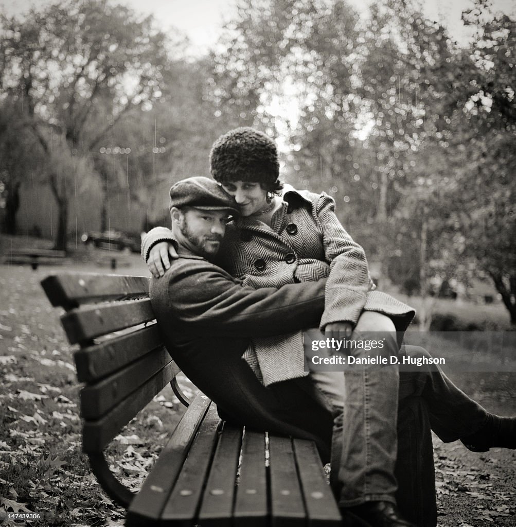 Couple sitting on bench in rain