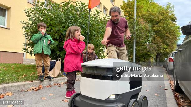 mature man showing a thumb up to a root delivering food home while his three children eating icecream - estland stock-fotos und bilder