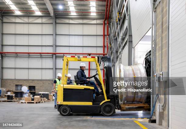 employee working at a distribution warehouse and moving a cable drum with a forklift - loading bay stock pictures, royalty-free photos & images