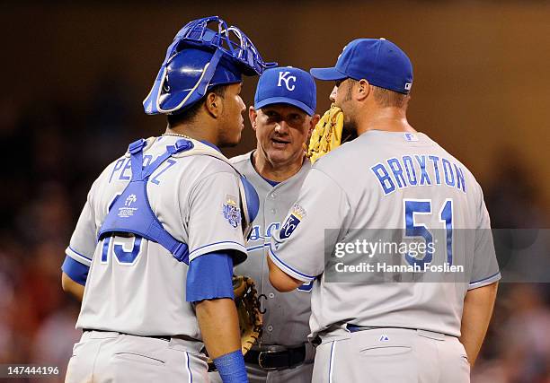 Dave Eiland of the Kansas City Royals speaks with Salvador Perez and Jonathan Broxton on the mound during the ninth inning against the Minnesota...